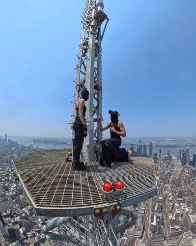 Angela Nikolau and Vanya Beerkus proposing on the antenna spire platform at the top of the Empire State Building with the Manhattan skyline below