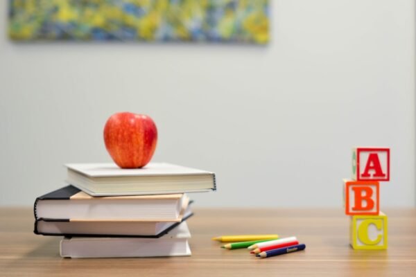Stack of books with a red apple on a desk symbolizing learning and modern education