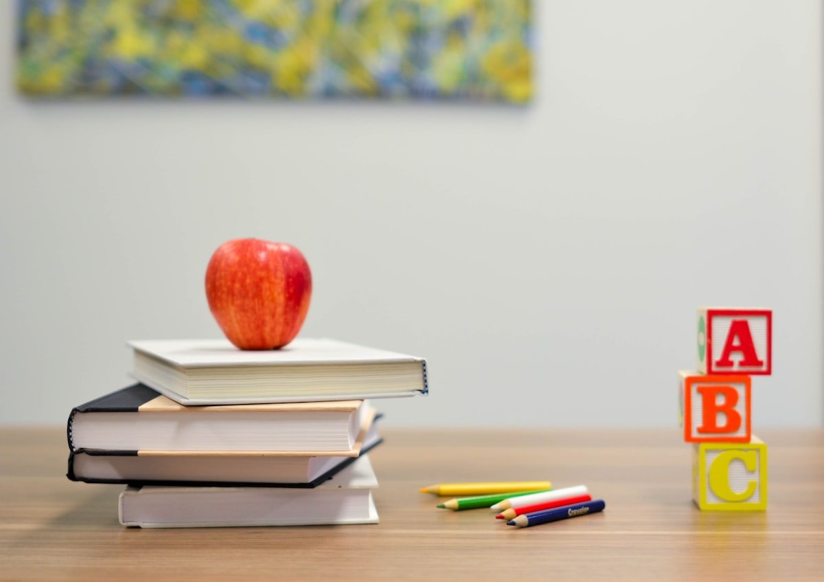 Stack of books with a red apple on a desk symbolizing learning and modern education