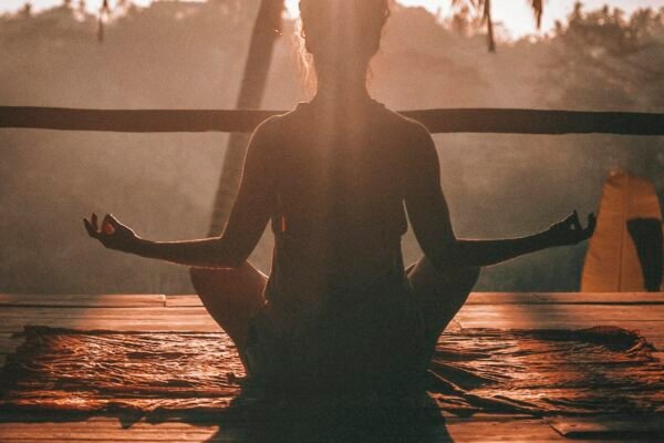 Person meditating in silhouette at sunrise reflecting a slow and mindful simple living lifestyle