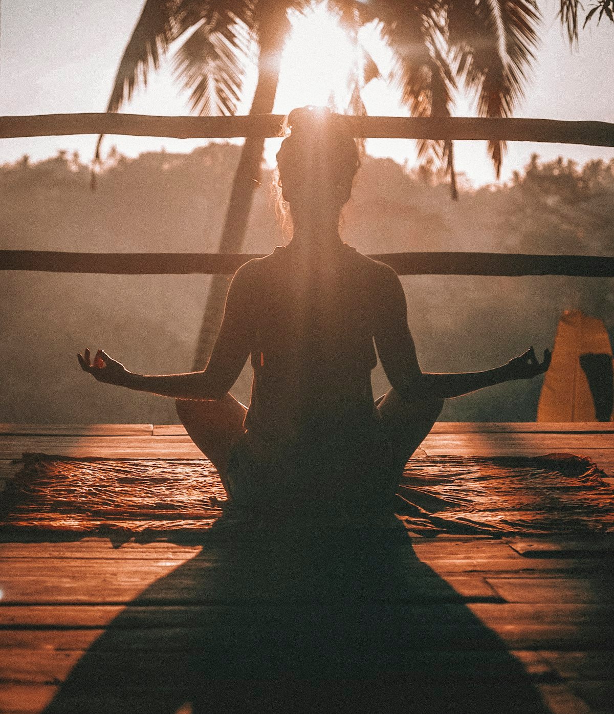 Person meditating in silhouette at sunrise reflecting a slow and mindful simple living lifestyle