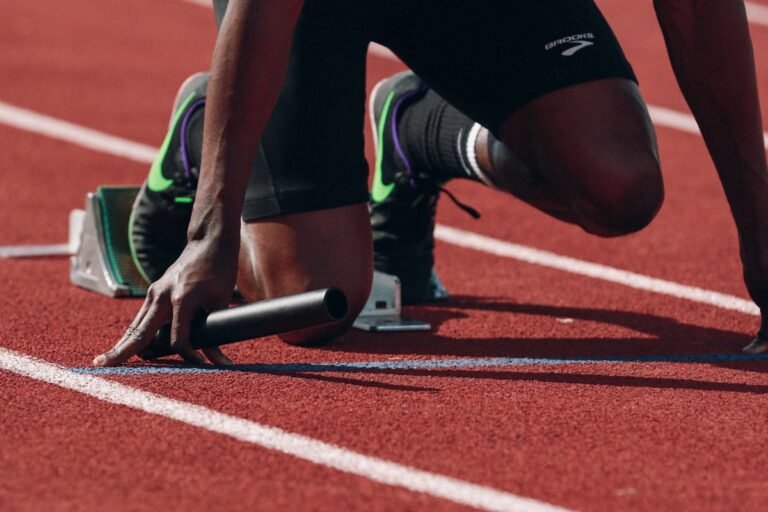 Sprinter crouched on starting blocks at a running track illustrating focus on athletic recovery and training