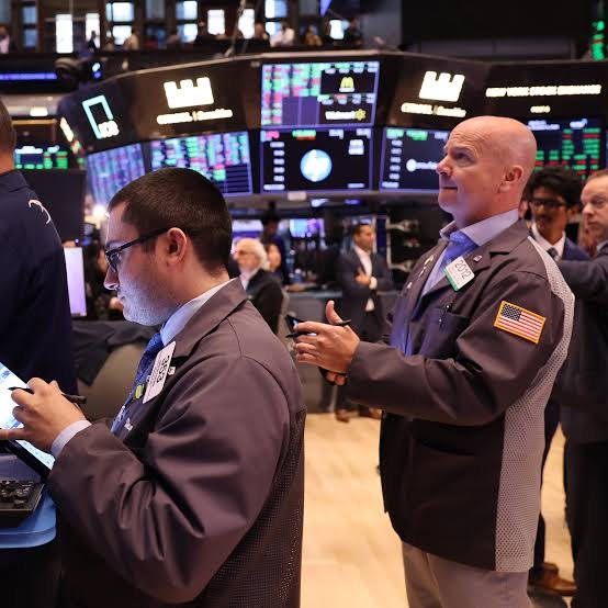 Traders on a stock exchange floor monitoring live market screens and index movements